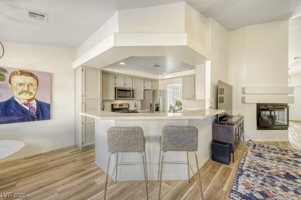 1536 Pony Ranch Circle Henderson, NV 89014 - Photo 11 of 24 Kitchen featuring a breakfast bar area, light countertops, appliances with stainless steel finishes, light wood-style floors, and a peninsula