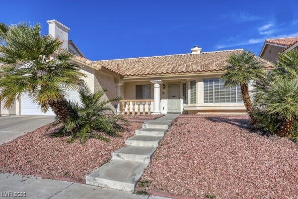 1536 Pony Ranch Circle Henderson, NV 89014 - Photo 2 of 24 Mediterranean / spanish home featuring a chimney, covered porch, a tiled roof, concrete driveway, and stucco siding