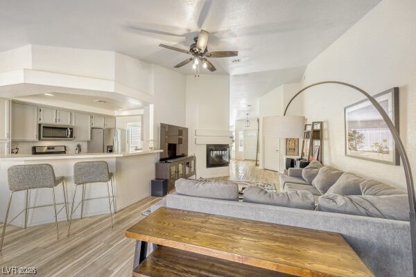 1536 Pony Ranch Circle Henderson, NV 89014 - Photo 8 of 24 Living room with a ceiling fan, light wood-style flooring, a multi sided fireplace, and a towering ceiling