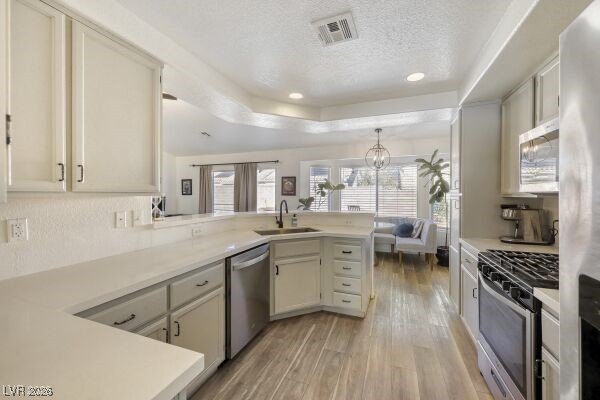 1536 Pony Ranch Circle Henderson, NV 89014 - Photo 9 of 24 Kitchen featuring appliances with stainless steel finishes, light countertops, a peninsula, light wood-style flooring, and recessed lighting
