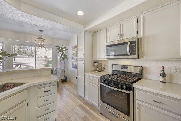 1536 Pony Ranch Circle Henderson, NV 89014 - Photo 10 of 24 Kitchen featuring stainless steel appliances, white cabinets, light wood-type flooring, decorative light fixtures, and recessed lighting