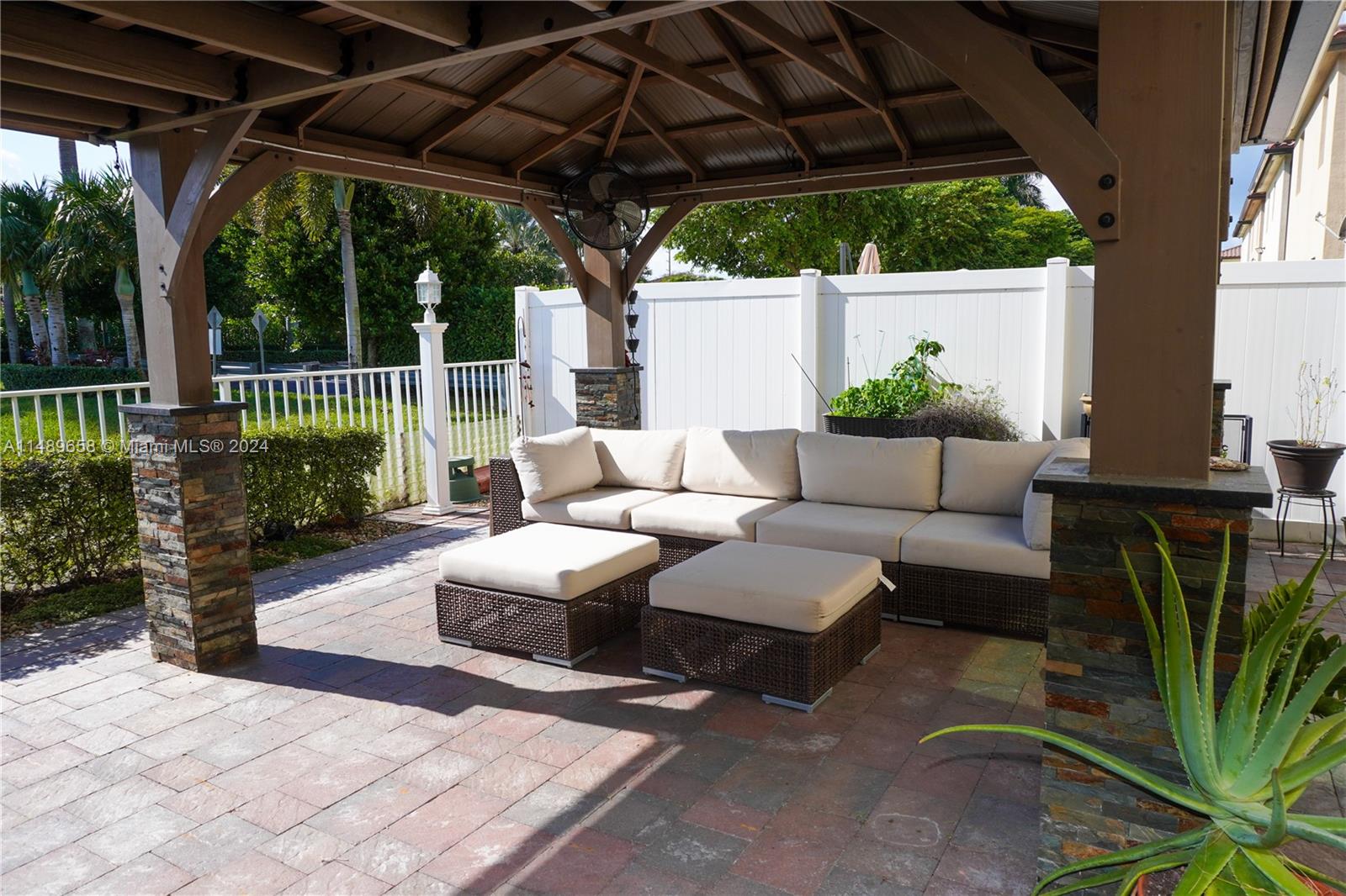 3522 West 88th Street Hialeah, FL 33018 - Photo 44 of 52 a view of a patio with couches table and chairs under an umbrella with a small yard