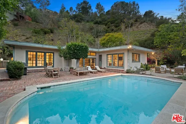 a house view with swimming pool and sitting area