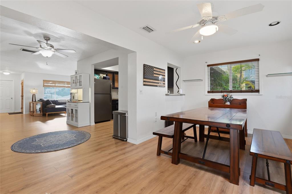 4576 Bliss Road Sarasota, FL 34233 - Photo 18 of 40 a dining room with wooden floor a chandelier fan a wooden table and chairs