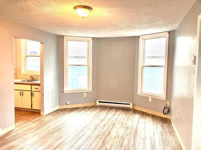 a view of an empty room with a window and wooden floor