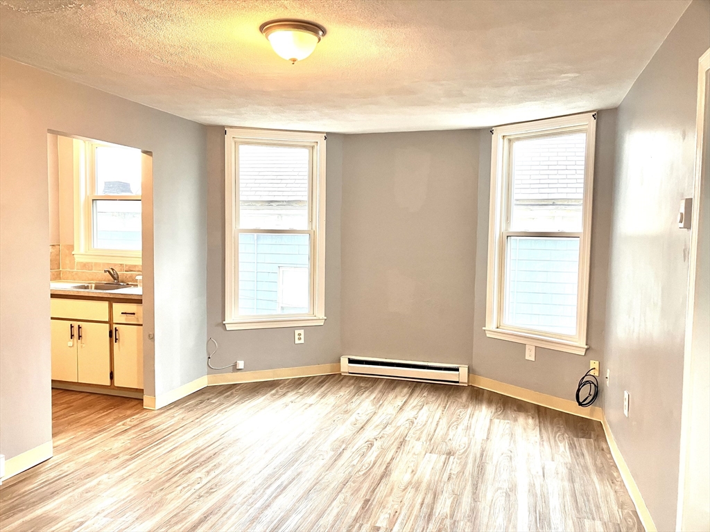 57 Rogers Avenue, Unit 2 Lynn, MA 01902 - Photo 2 of 9 a view of an empty room with a window and wooden floor