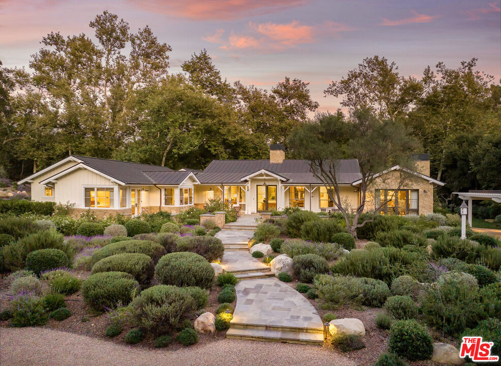 a view of a house with a big yard plants and large tree