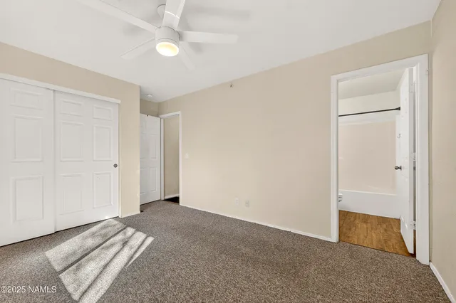 an empty room with closet and a ceiling fan