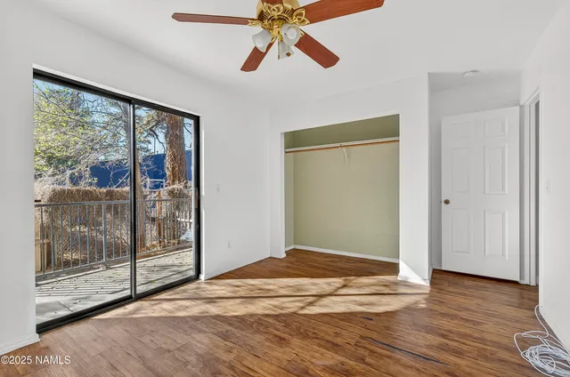 a view of empty room with wooden floor and fan
