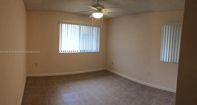 an empty room with a window and chandelier fan