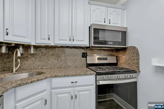 a kitchen with granite countertop a stove and a microwave