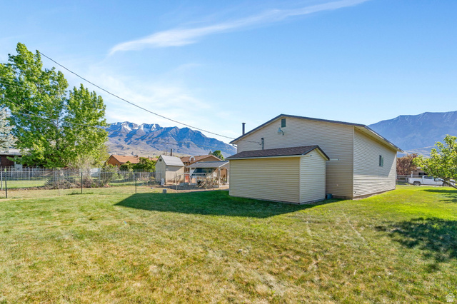 377 North 650 East, Unit 9 Orem, UT 84097 - Photo 7 of 9 Expansive green lawn with mountain backdrop, featuring a two-story residence with light-colored siding and a detached storage shed