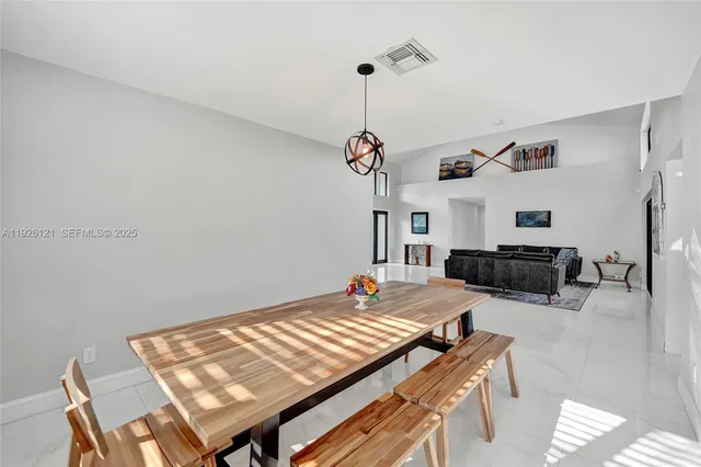 a kitchen with stainless steel appliances granite countertop a stove top oven a refrigerator a sink a dining table and chairs with wooden floor