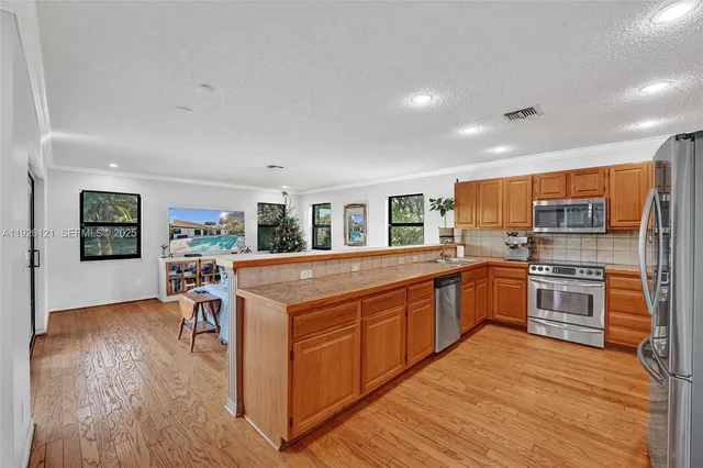 a kitchen with stainless steel appliances granite countertop a sink and wooden cabinets