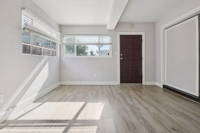 an empty room with wooden floor and windows