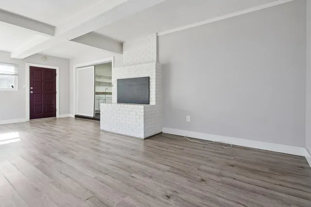 a view of an empty room with wooden floor and cabinet