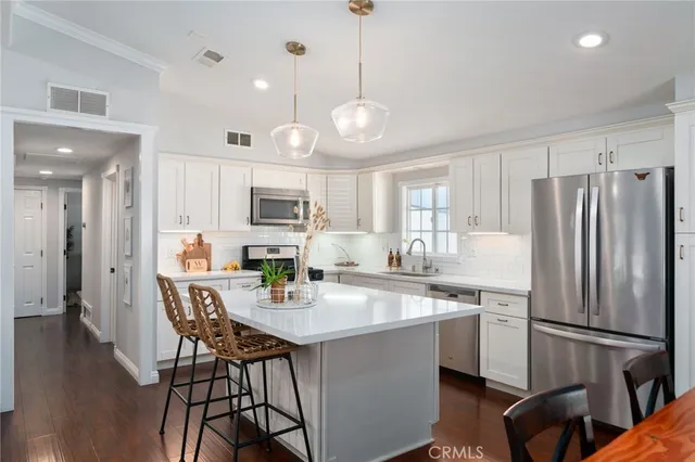 a kitchen with refrigerator a sink and chairs