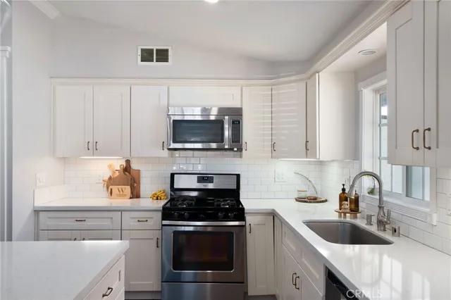 a kitchen with white cabinets a sink stove and microwave