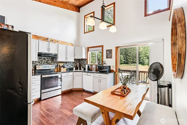 a kitchen with stainless steel appliances granite countertop a stove top oven a sink dishwasher a dining table and chairs with wooden floor