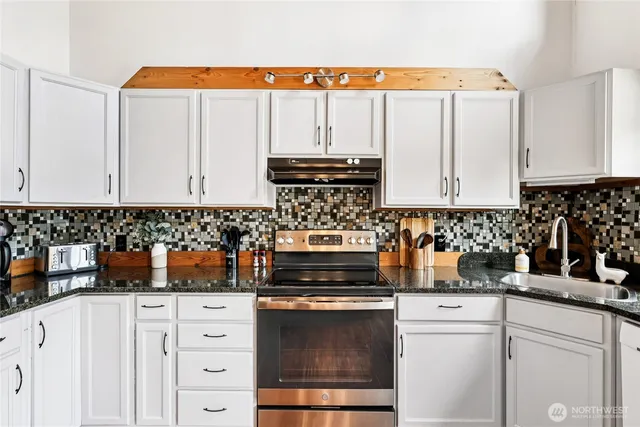 a kitchen with a stove and white cabinets