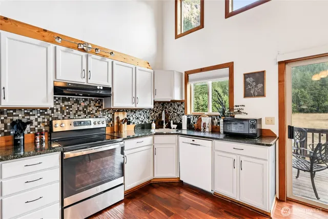 a kitchen with granite countertop white cabinets and white appliances
