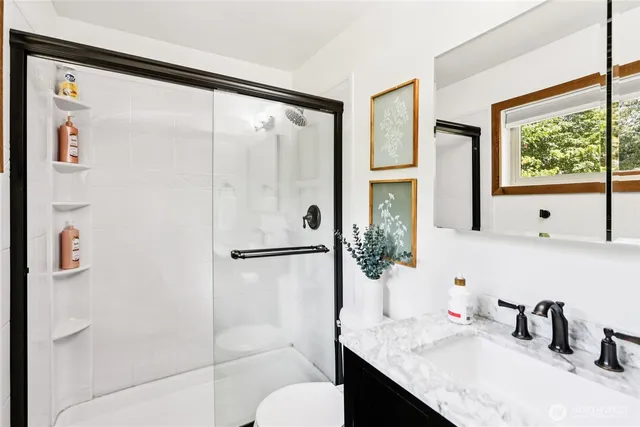 a bathroom with a granite countertop sink mirror and a shower