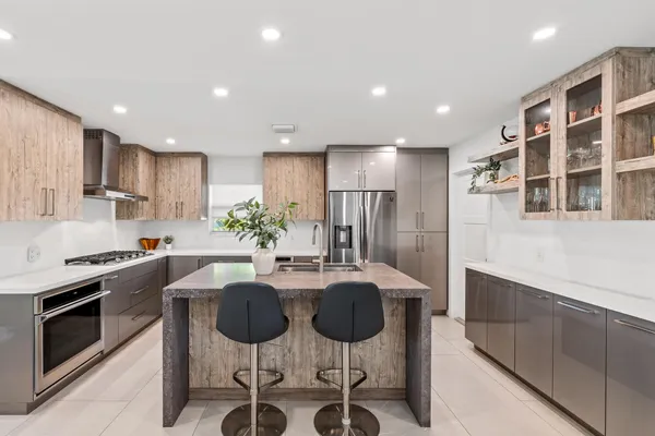 a kitchen with stainless steel appliances kitchen island granite countertop a kitchen island and chairs in it