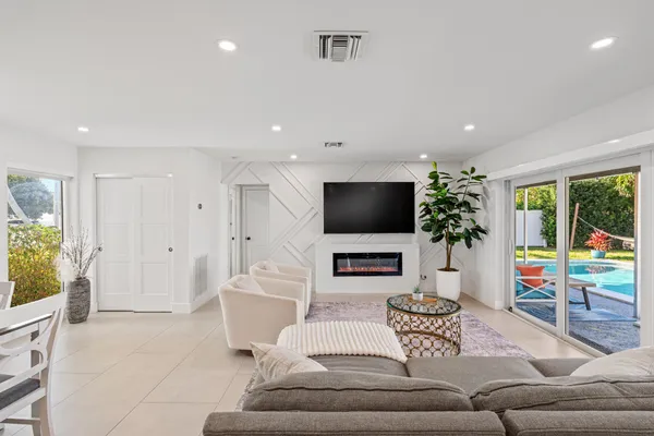 a living room with furniture a flat screen tv and a large window
