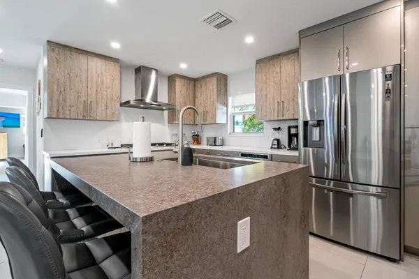 a kitchen with kitchen island a counter top space a sink stainless steel appliances and cabinets