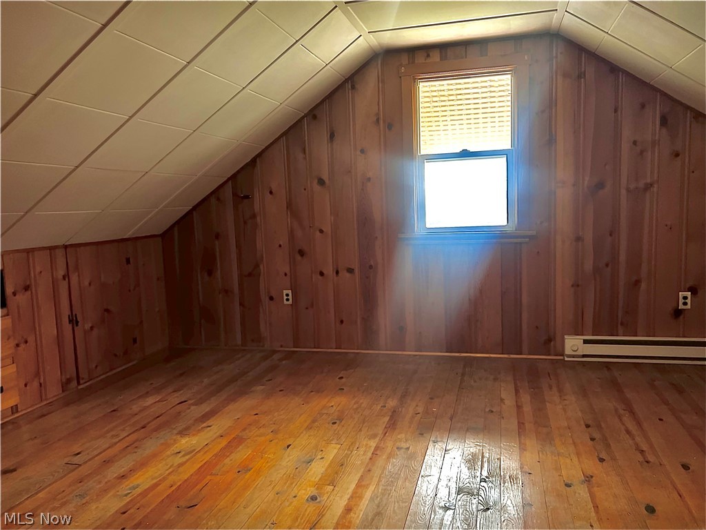 67 Forbes Road Bedford, OH 44146 - Photo 13 of 20 Additional living space with hardwood / wood-style flooring, vaulted ceiling, wood walls, and a baseboard radiator