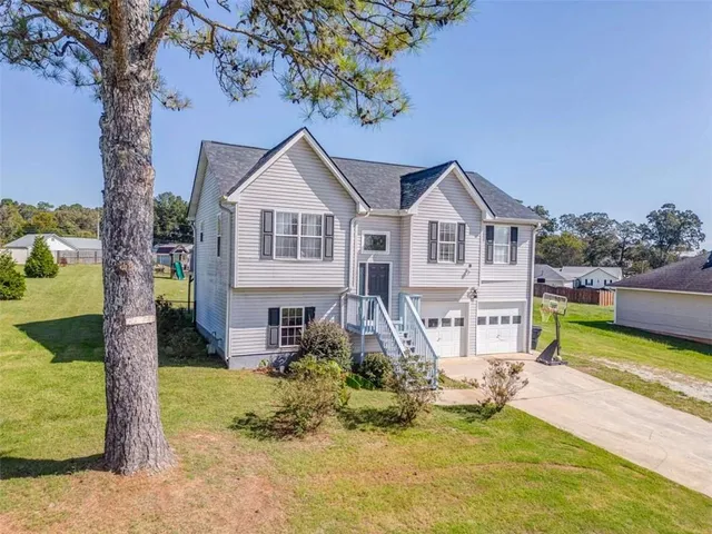 a view of a house with a big yard and large trees