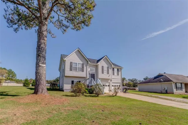 a view of a house with a yard and large trees