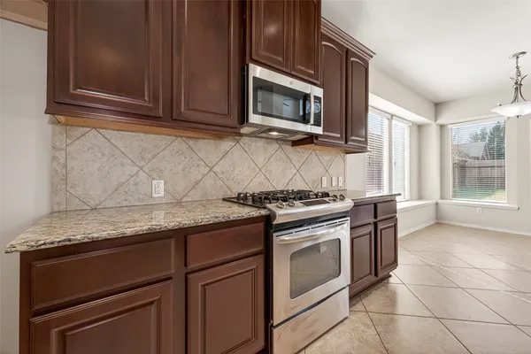 a kitchen with granite countertop a stove top oven microwave and cabinets