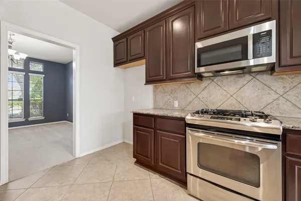 a kitchen with granite countertop a stove top oven microwave and cabinets