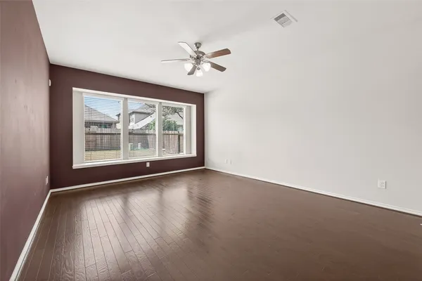 a view of an empty room with wooden floor and a window