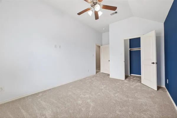 an empty room with a chandelier fan and closet area
