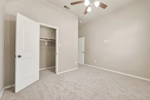an empty room with closet and a ceiling fan