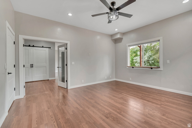2154 Wasatch Boulevard Sandy, UT 84092 - Photo 44 of 55 Empty room with a barn door, light wood-style flooring, recessed lighting, and ceiling fan