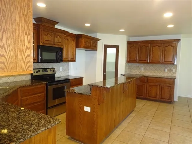 a kitchen with stainless steel appliances granite countertop a stove top oven a sink dishwasher and a microwave oven on the blue kitchen countertops