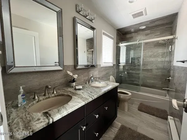a bathroom with a sink double vanity granite tub and a mirror