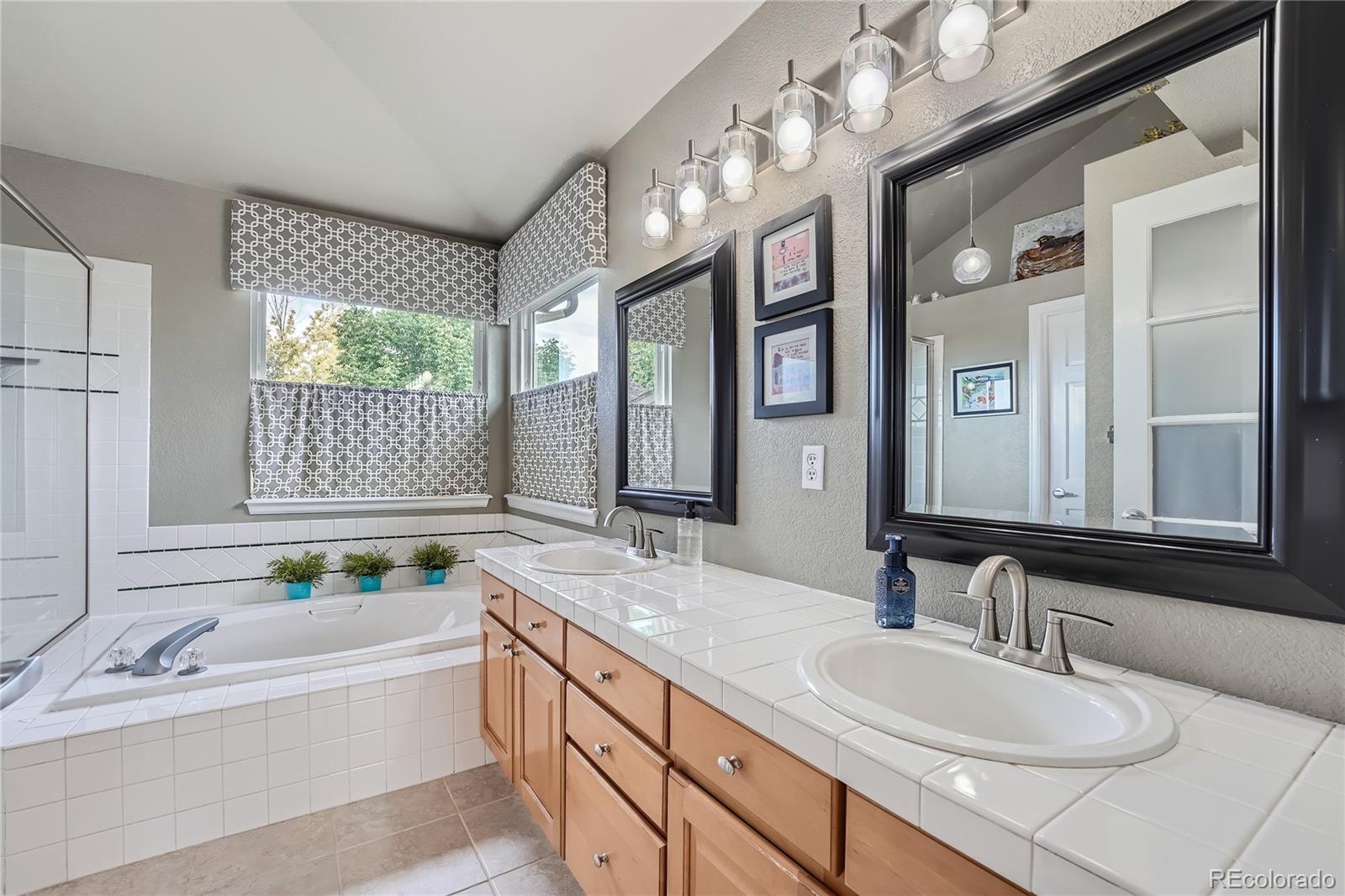 9538 La Quinta Drive Lone Tree, CO 80124 - Photo 23 of 41 a bathroom with a granite countertop double vanity sink a mirror and a bathtub