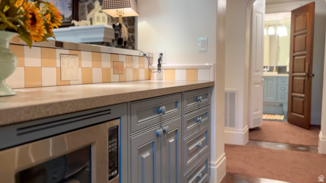 426 West Center Street Parowan, UT 84761 - Photo 69 of 107 Built-in stainless steel microwave, light gray cabinetry with decorative knobs, and a patterned tile backsplash featuring checkerboard and accent tiles