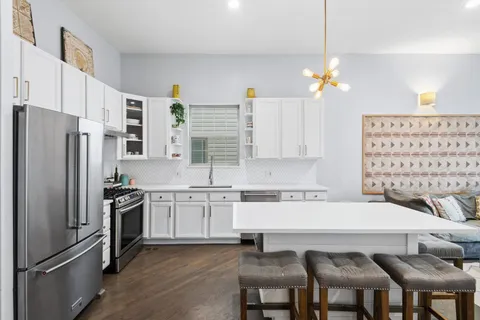 a kitchen with stainless steel appliances granite countertop a stove a refrigerator a oven a white table and chairs