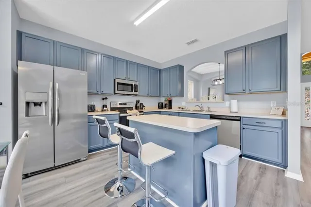 a kitchen with kitchen island granite countertop wooden cabinets and refrigerator