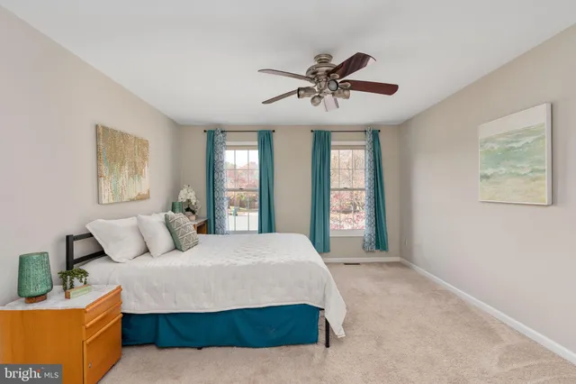 an empty room with a chandelier fan and windows