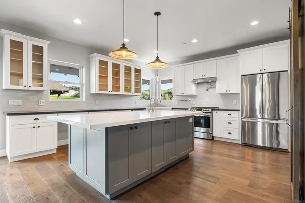 a kitchen with stainless steel appliances granite countertop a refrigerator a sink dishwasher a oven with white cabinets and wooden floor