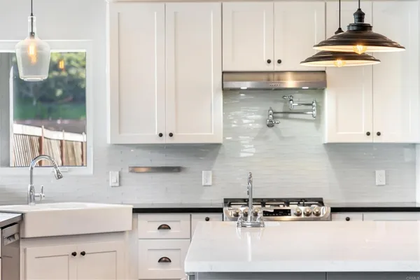 a kitchen with kitchen island granite countertop a sink a stove and white cabinets