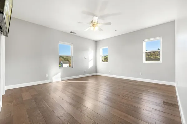 an empty room with wooden floor chandelier and windows