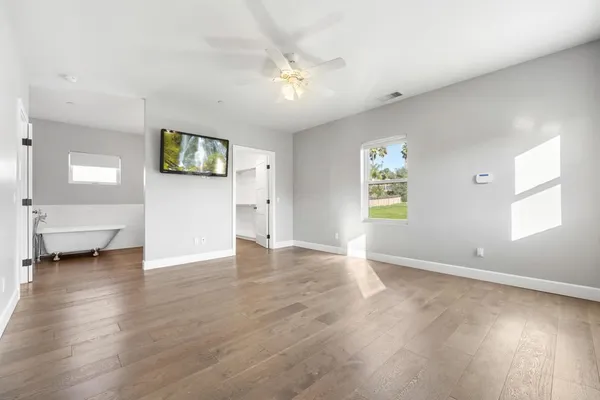 a view of an empty room with a window and wooden floor