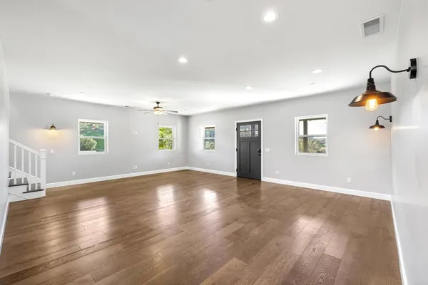 a view of an empty room with window and wooden floor